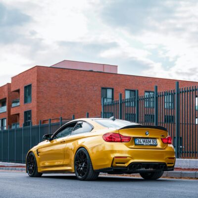A striking yellow BMW sports car parked near a red brick building in Ankara, Türkiye.