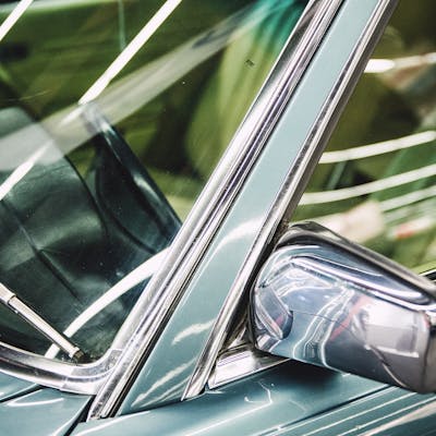 Detailed image of a luxury car's side mirror, window, and chrome trim.